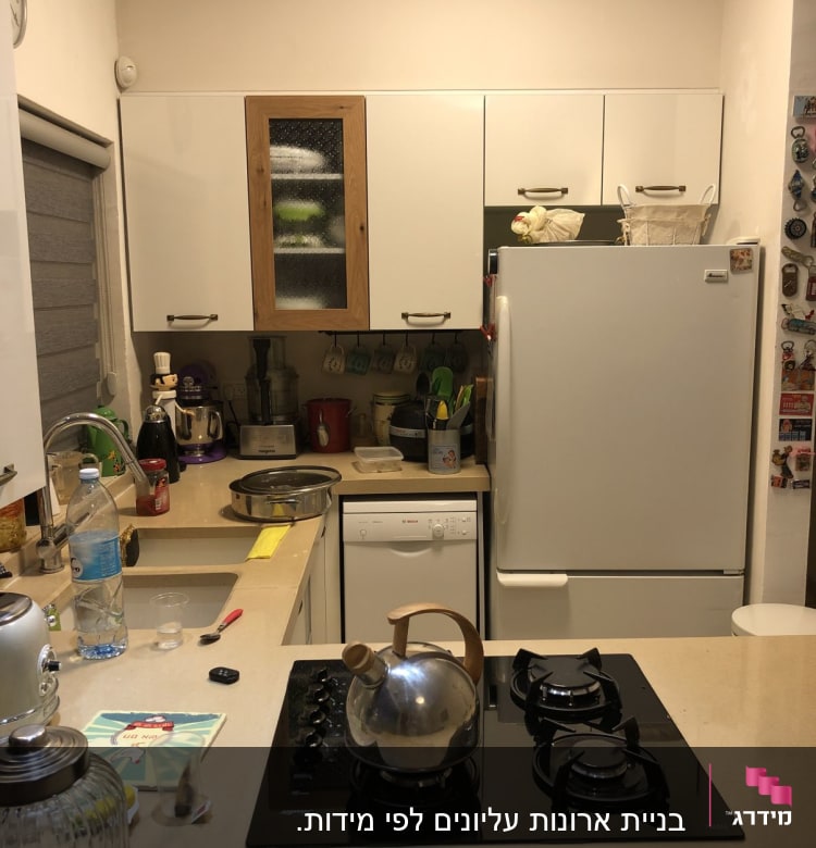 מטבח עם קומקום על כיריים, מקרר וארונות לבנים